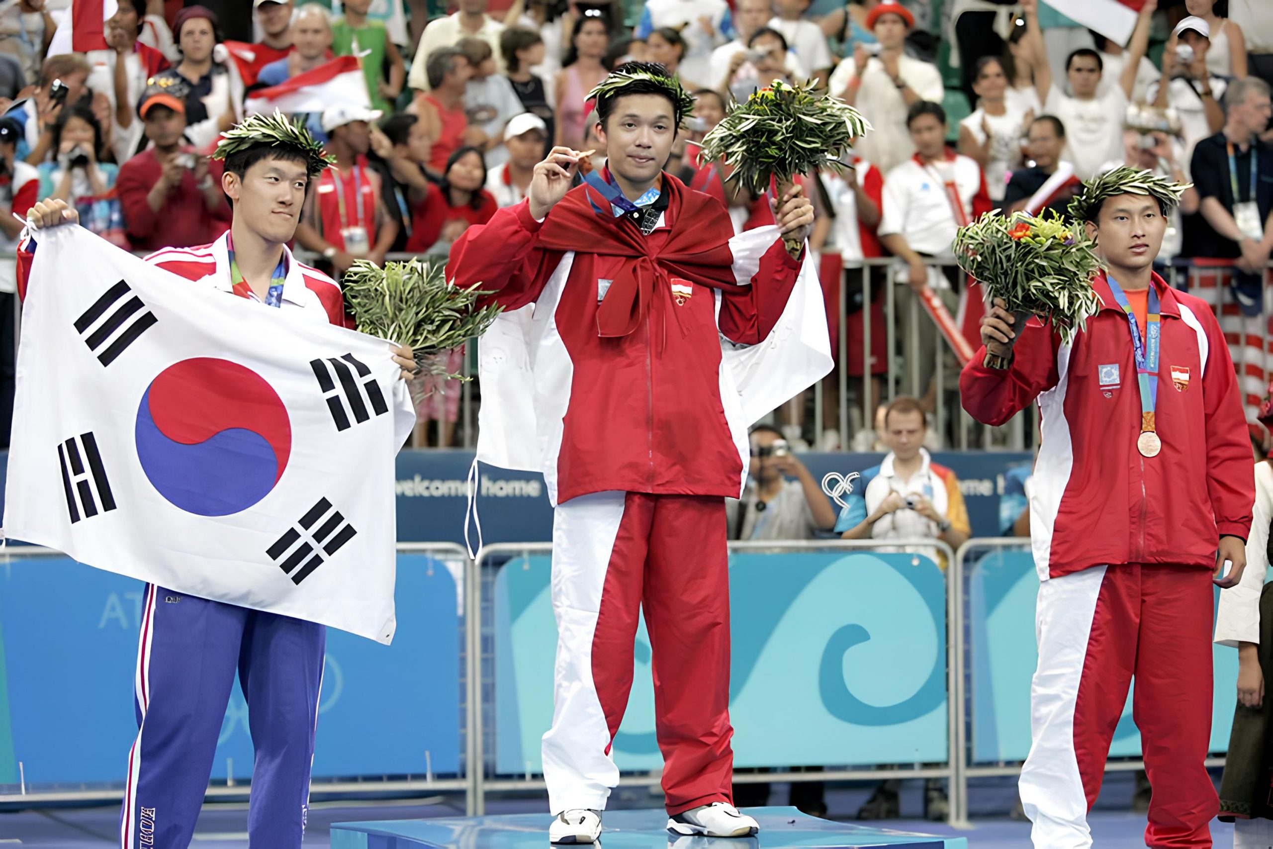 Taufik Hidayat (tengah) dan Soni Dwi Kuncoro (kanan) mempersembahkan medali emas dan medali perunggu dari cabor bulu tangkis nomor tunggal putra pada Olimpiade Athena 2004. Medali perak didapat Shon Seung-Mo dari Korea Selatan. (Foto:AFP)