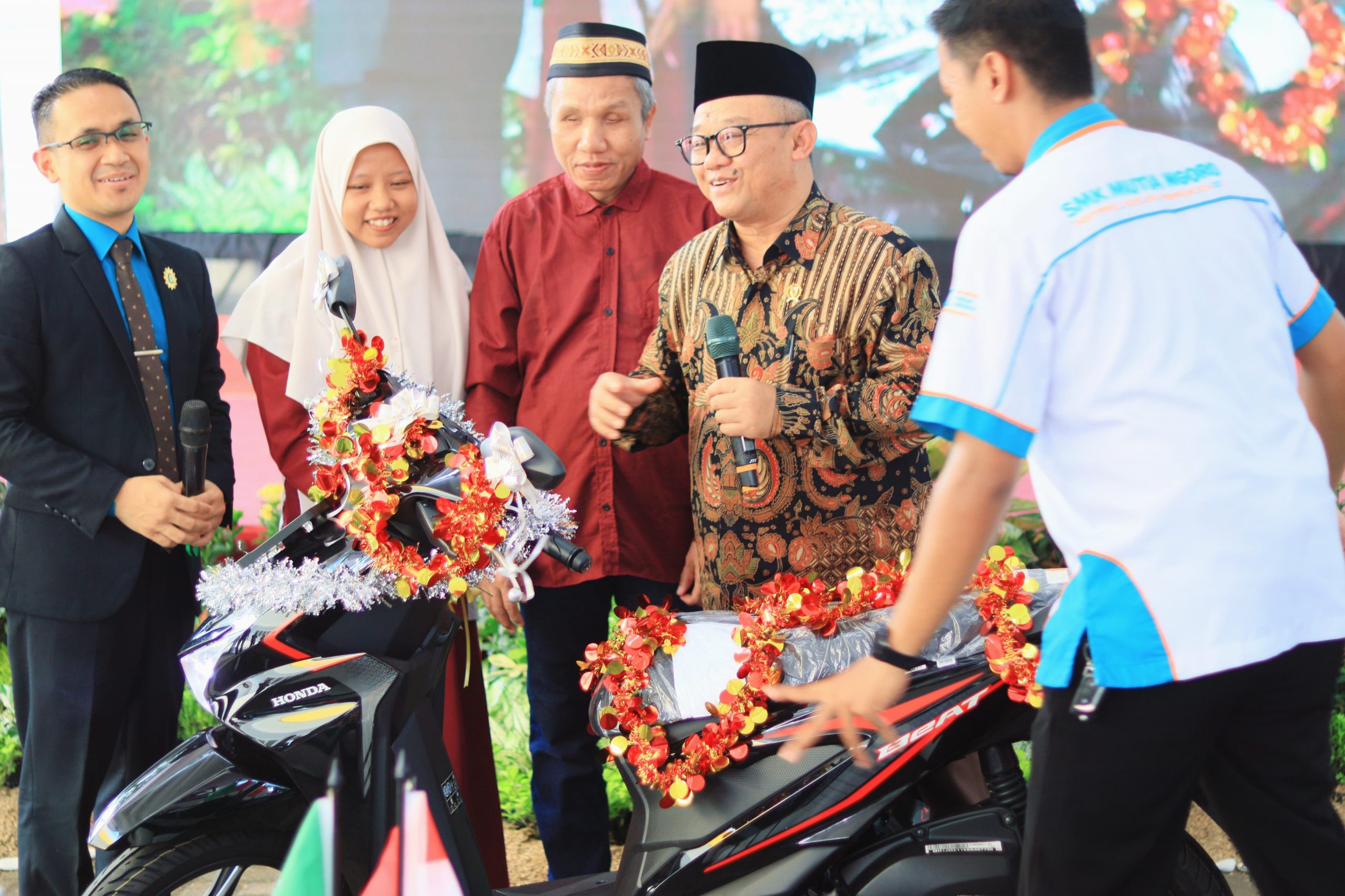 Dari kiri: Kepala SMK Mutia Ngoro Ednan Rudianto, murid XII Multimedia 1 SMK Mutia Ngoro Fidyatun Shoimah, Mohammad Syafi'i, dan Mendikdasmen RI Prof Abdul Mu'ti (batik), saat penyerahan doorprize utama. (Foto: Dok. Mutia)